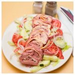 Chef Salad. This picture depicts a salad that consists of, lettuce, tomato, peppers and onions, sliced cucumbers, rolled up cold cuts which consist of roast beef turkey ham Swiss and American SlicedAnd served on a white platter on top of Johnys yellow countertop