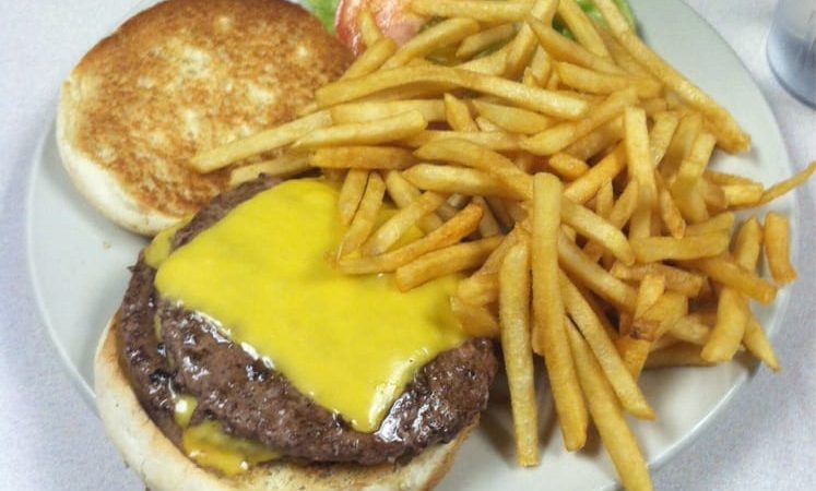 Double Cheese Burger Deluxe. This picture depicts 2 Quarter-pound beef Stacked on top of each other served with shoestring french fries on the side and accompanied with Sliced lettuce and tomato on top of a whitepatties