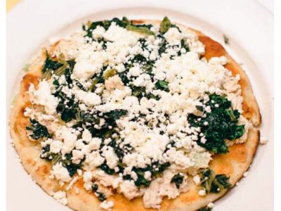 Great Alexander. This picture depicts an order of fresh tuna salad that is topped with spinach and feta cheese served open face on a pita bread that is on a white platter served on Johnys countertop